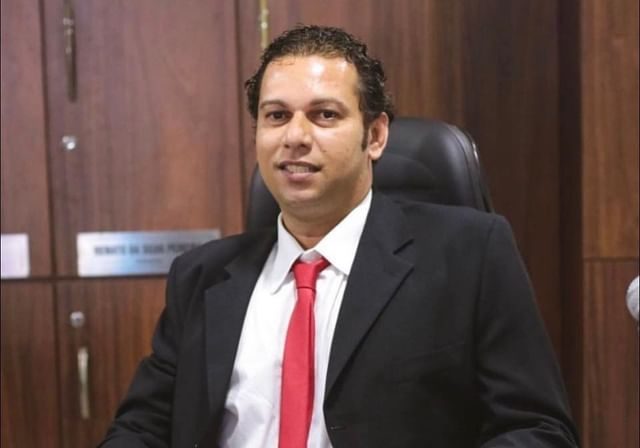 O vereador Kleber Ferreira da Costa de terno escuro sentado atrás de uma mesa