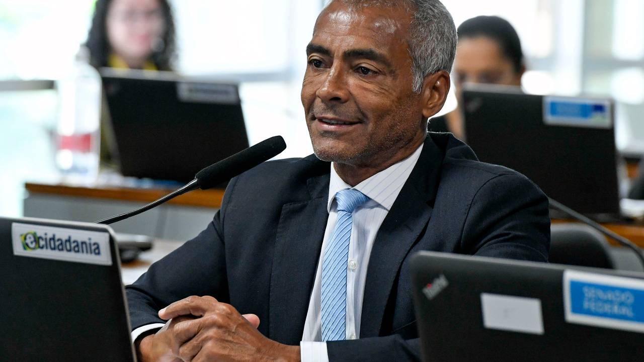 o senador romário sentando atrás de uma tela e um microfone vestindo roupa social