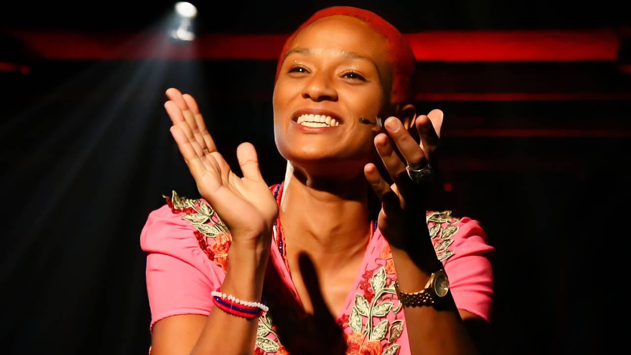 atriz de cabelo curto batendo palma num palco iluminado