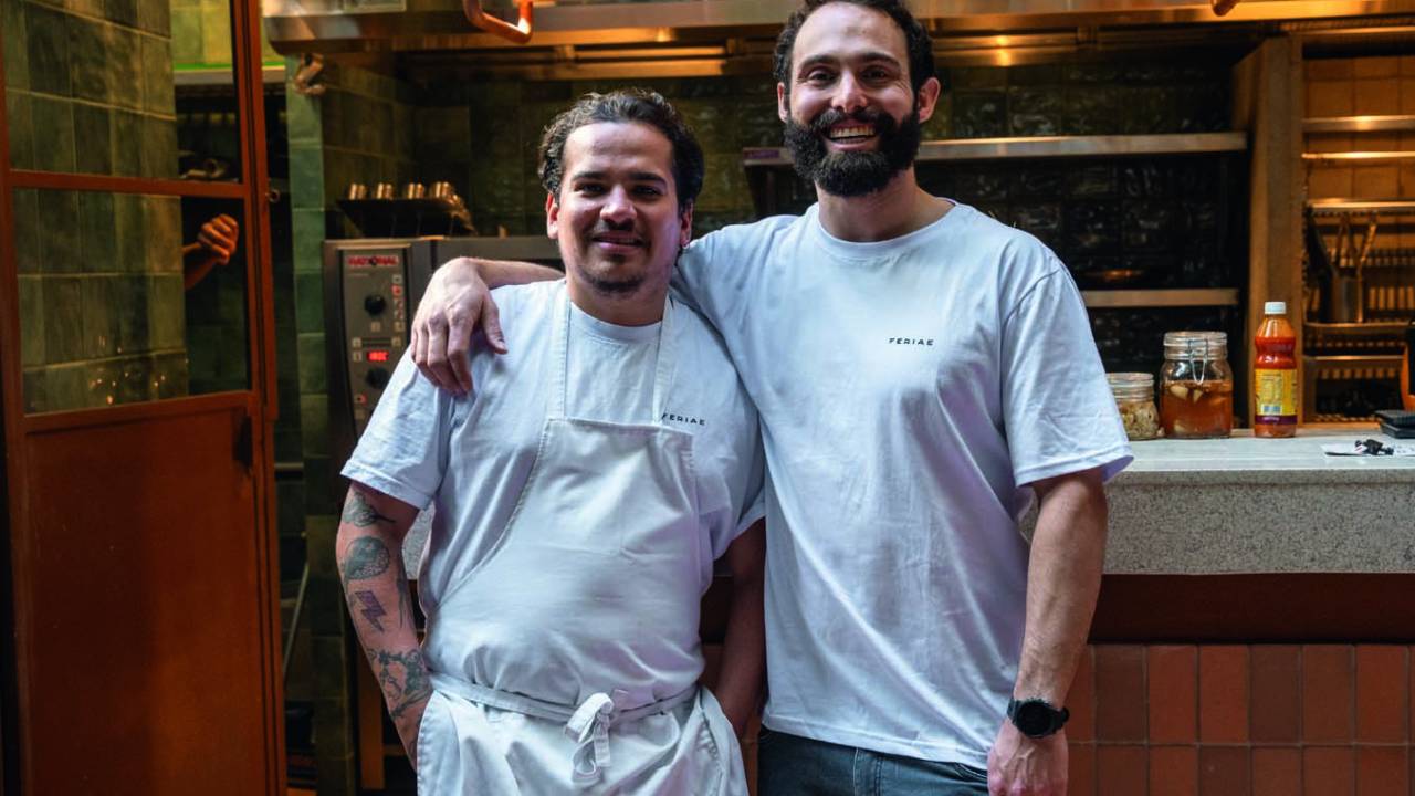 Dois homens de branco um ao lado do outro abraçados.