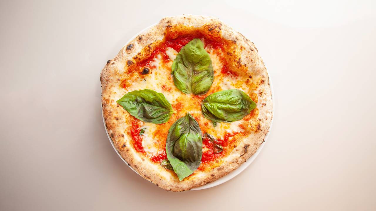 Foto aérea de pizza com folhas de manjericão.