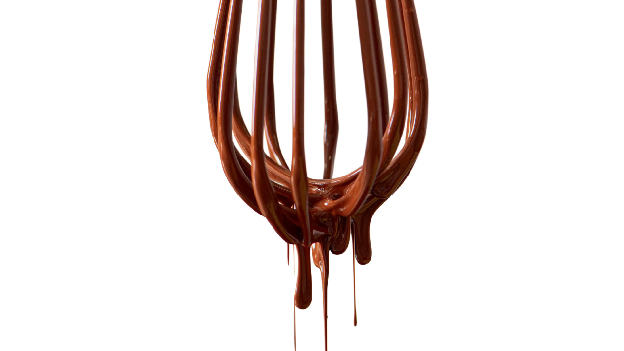 Fouet escorrendo chocolate em fundo branco.