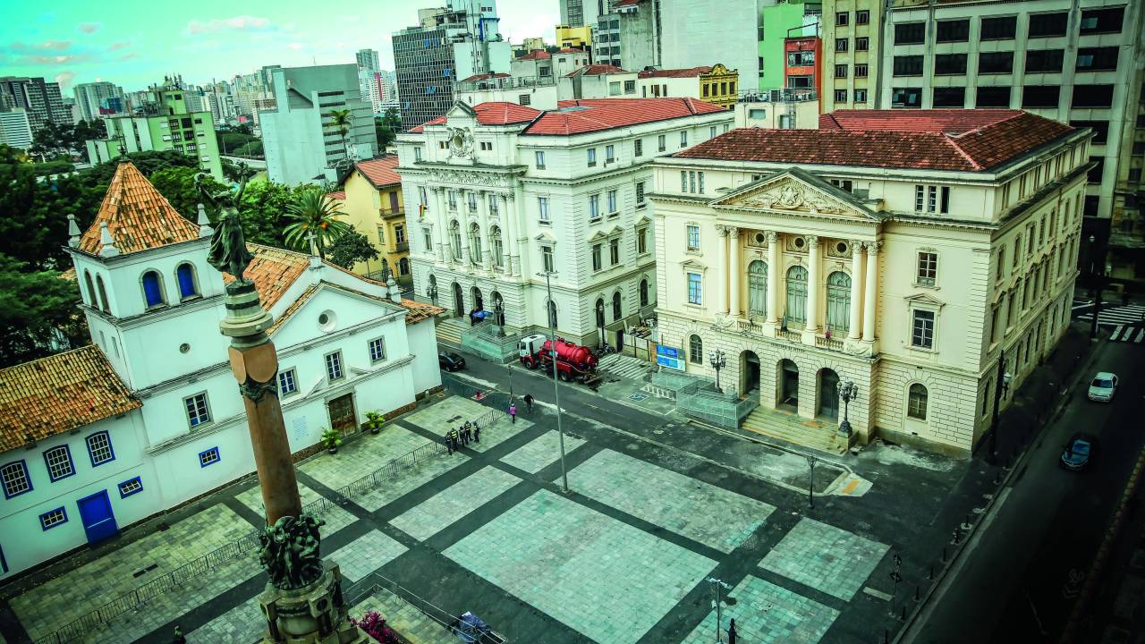 Foto aérea de dois palacetes e pátio vazio em frente.