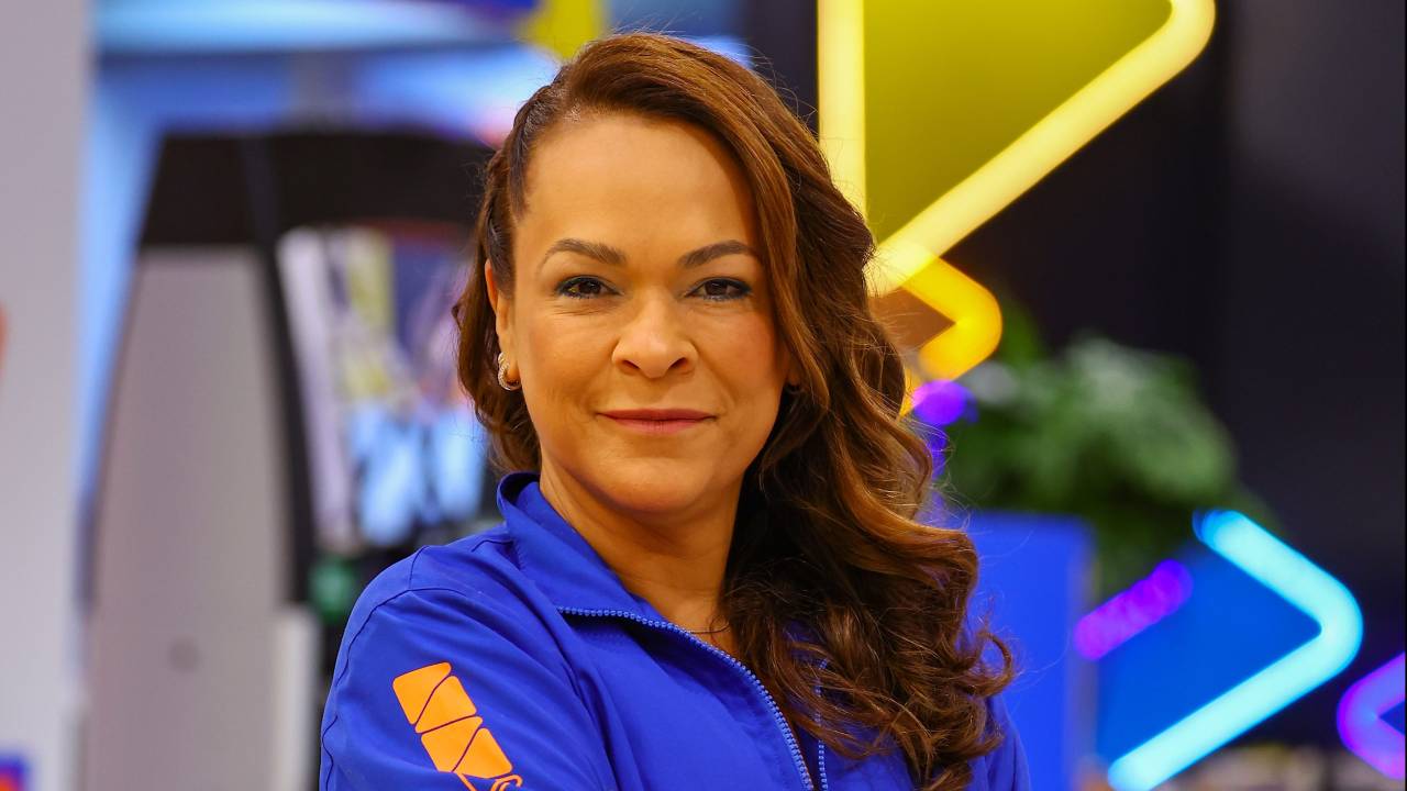 Imagem mostra Bárbara, usando macacão de posto, em posto de gasolina Ipiranga. Ela está de braços cruzados e com leve sorriso