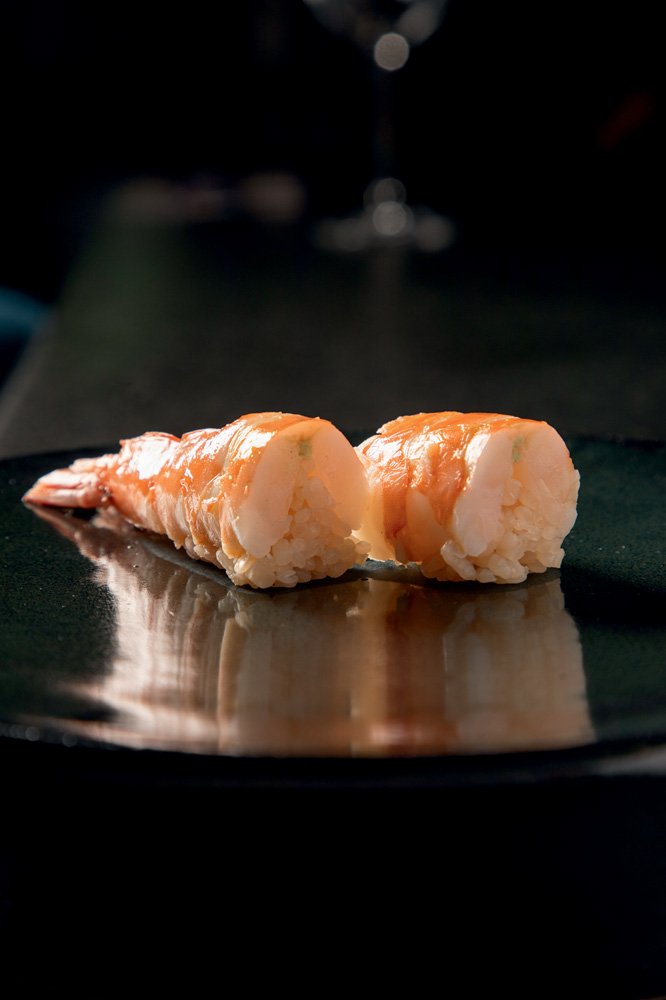 Maza Dois sushis de camarão sobre tampo preto.