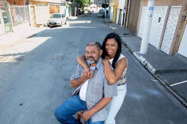 perla graziela e wilson antonio Imagem mostra pai e filha abraçados, com a filha por trás do pai. Eles seguram as mãos e estão no meio de uma rua residencial