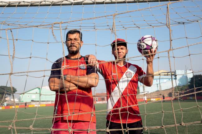 alberto pardini e dirceu martins de oliveira Imagem mostra pai. Dirceu, e filho, Alberto, em campo de futebol. Os dois estão dentro de gol e olham para câmera por entre as redes do gol. O filho segura no braço esquerdo uma bola de futebol.