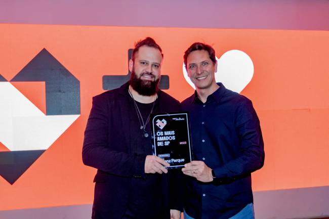 Imagem mostra Mike e Rafael segurando placa juntos do Allianz Parque