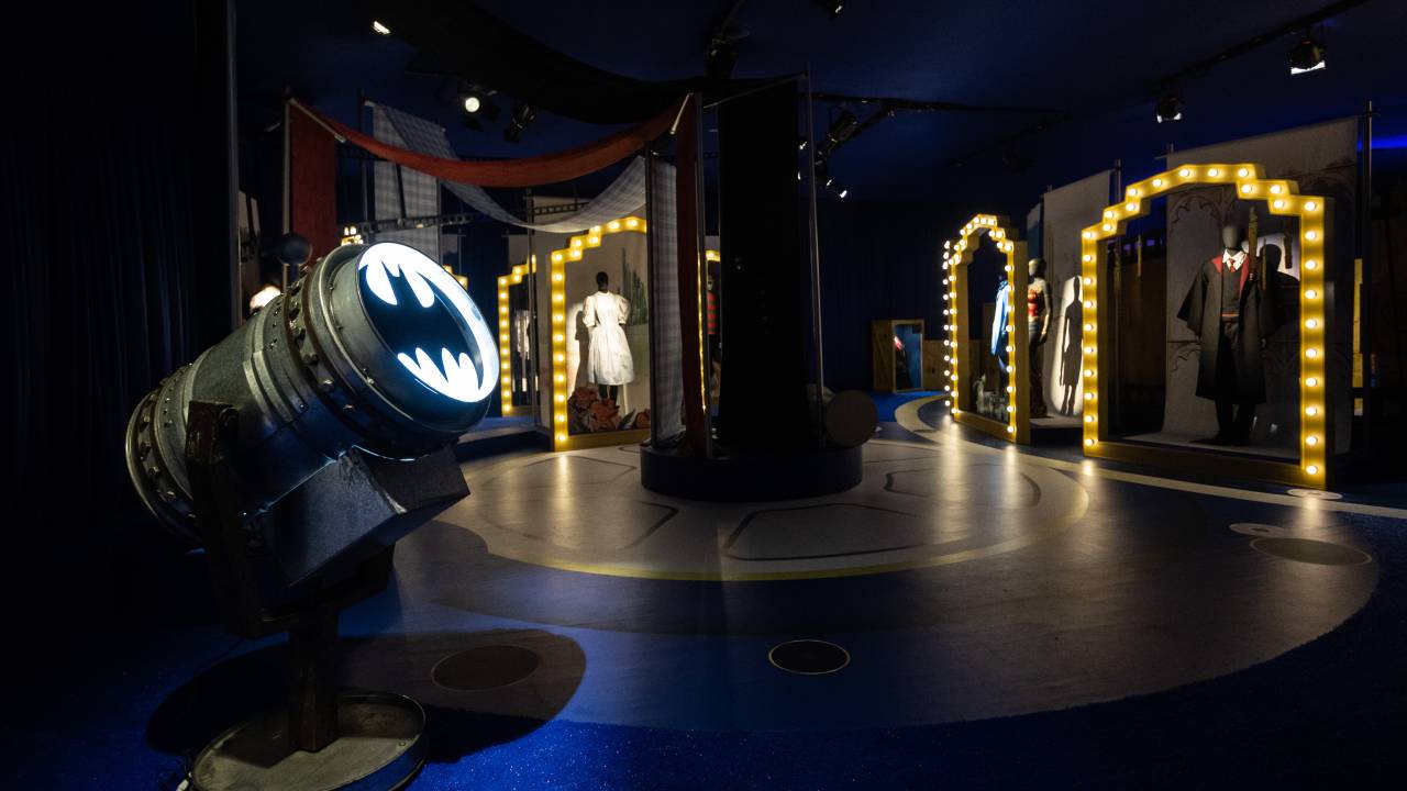 Tenda com o símbolo do Batman e outras roupas de filmes da Warner ao fundo.