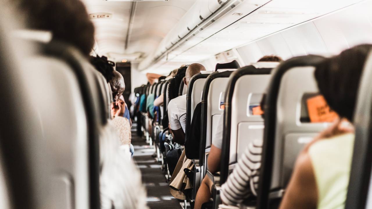 um avião por dentro. pessoas sentadas nas poltronas.