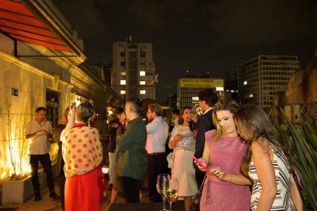 mais amados 2023 Imagem mostra várias pessoas conversando em terraço, durante a noite