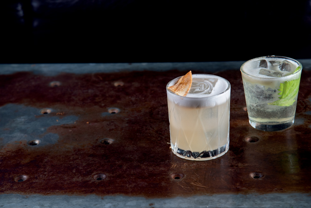 COMER & BEBER 2023 – Trago Bar Sobre uma mesa de ferro, dois copos de vidro com drinques diferentes.