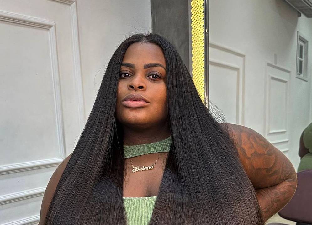 uma mulher negra de cabelos longos e lisos olhando séria para a câmera