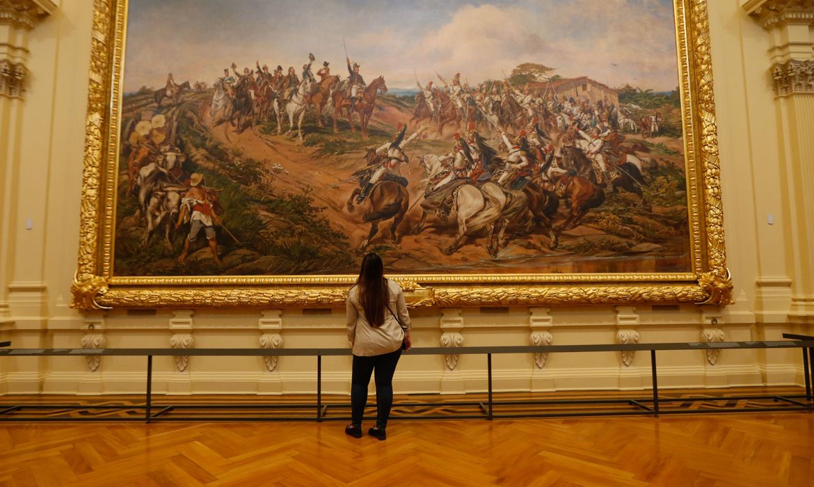 uma mulher observa o quadro 'independência ou morte', de pedro américo