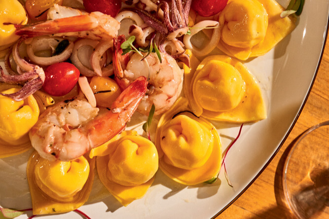 Metade de um prato de massa tortellini com camarão e frutos do mar.