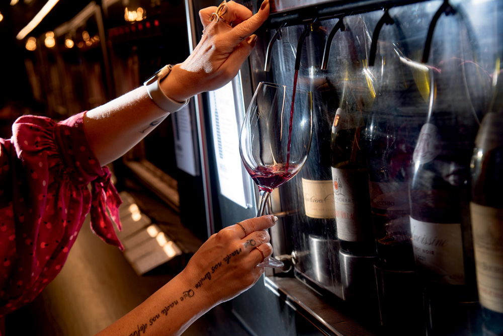 Feira dos Campeões 2023 – Bardega Mão servindo vinho tinto em máquina automática com garrafas dentro.