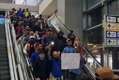 pessoas descendo uma escada rolante protestando