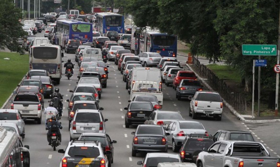 uma avenida com trânsito de carros e ônibus