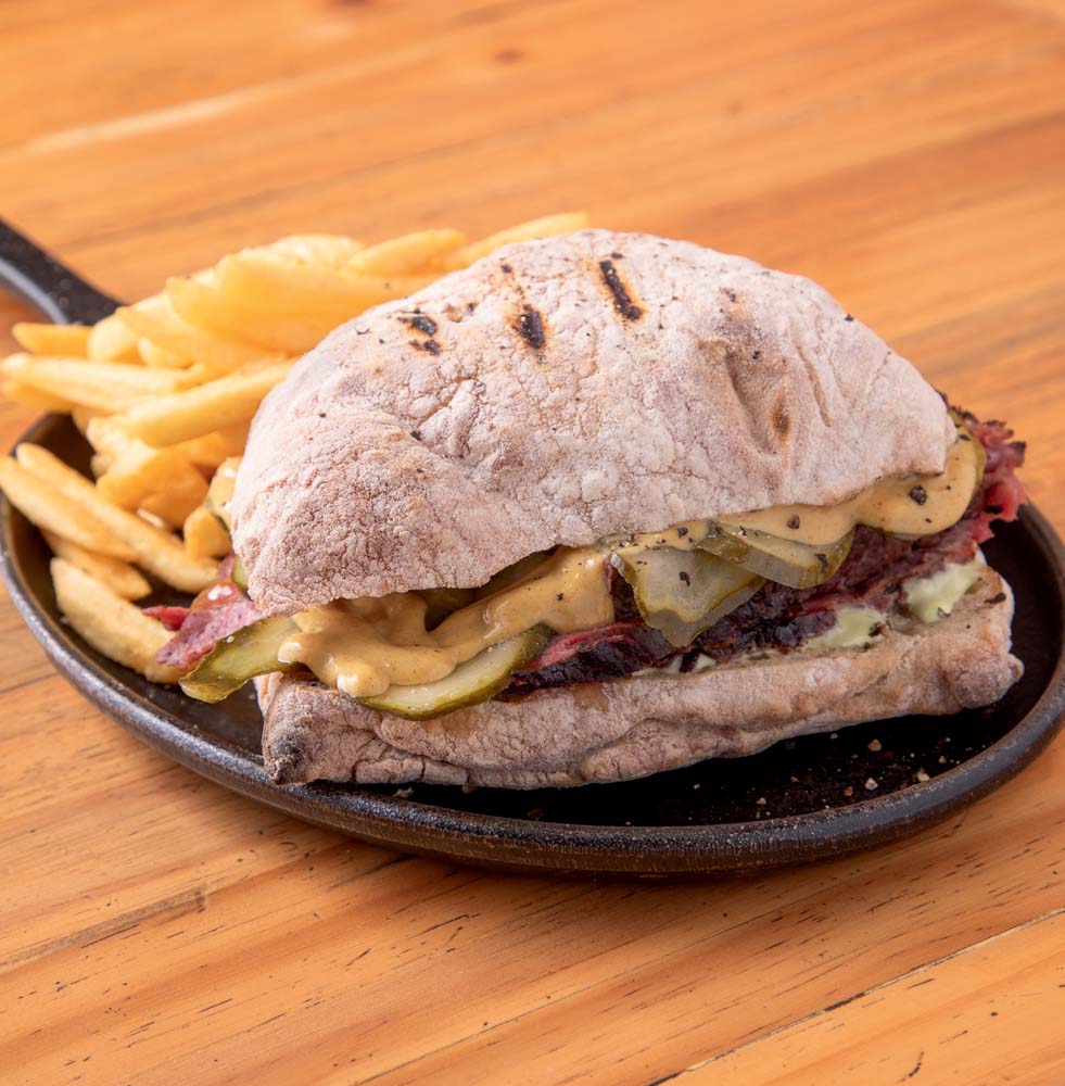 Sisttina Sandwich Shop Em um prato redondo preto, um sanduíche acompanhado de fritas.