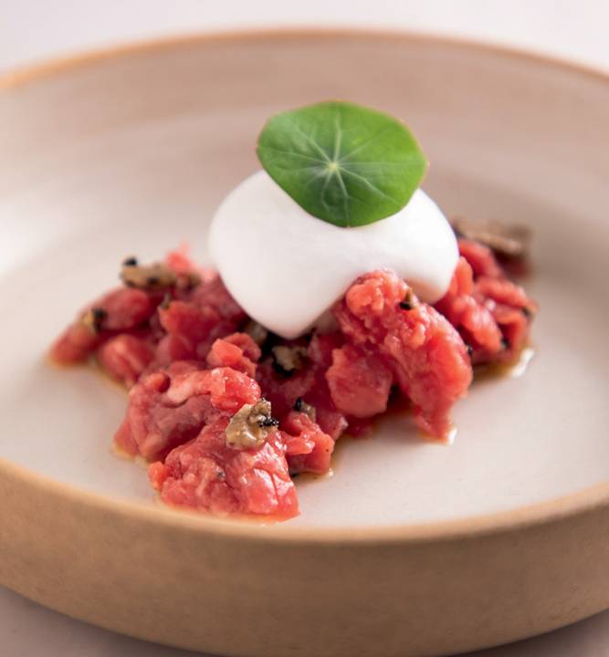 Prato fundo de cerâmica com tartare de carne coberto com bolota de muçarela de búfala