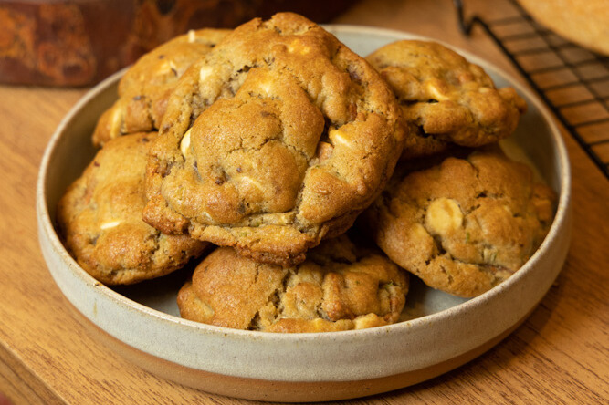 Um pote com vários cookies dentro em cima de uma mesa de madeira.