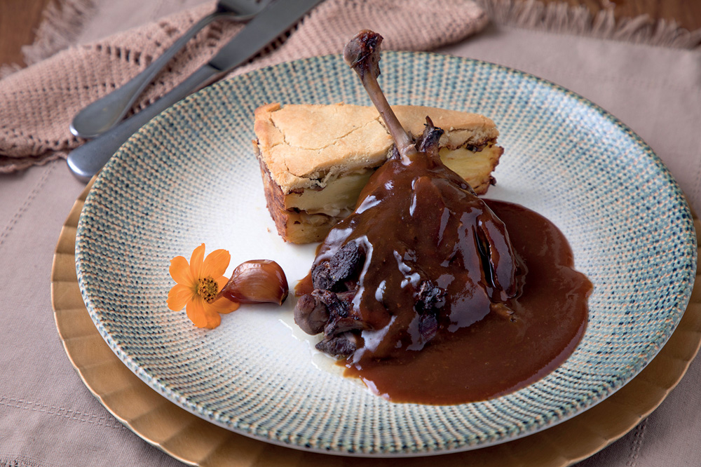 Ruella Bistro prato-de-ceramica-com-coxa-de-pato-com-molho-ao-lado-de-pedaço-de-torta