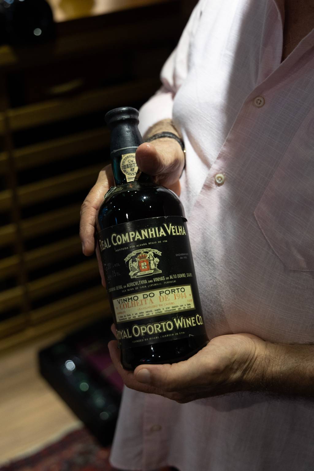 RONNIEVONADEGA8 Mãos brancas seguram garrafa escura de vinho com o título