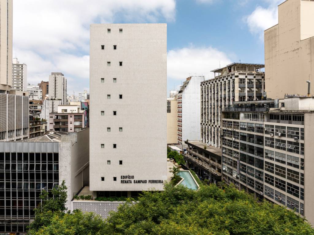 default Edifício Renata visto de frente, prédio branco com piscina no terraço à direita e praça com árvores à frente
