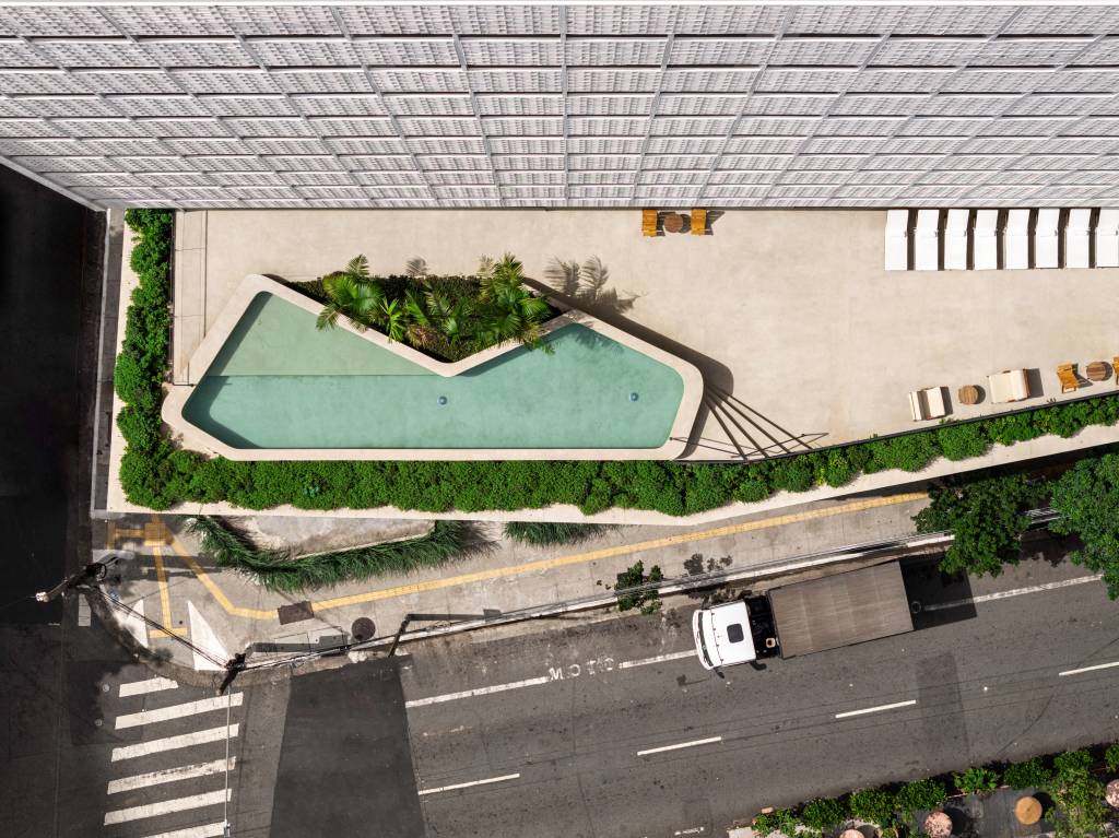 default Vista aérea de prédio branco com parede vazada em pequenos quadrados e piscina no terraço da área inferior