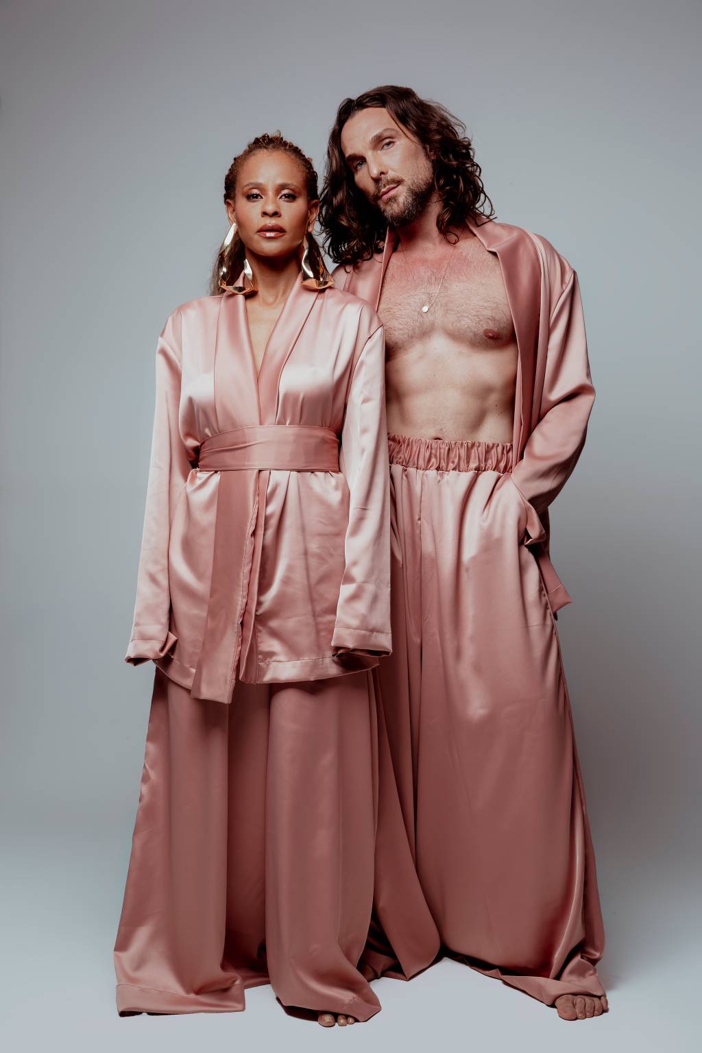 Aline Wirley e Igor Rickli-Crédito Jeff Porto-Divulgação (3) Mulher negra e homem branco, ambos de cabelos longos, posam de pé lado a lado vestindo peças em tom rosé
