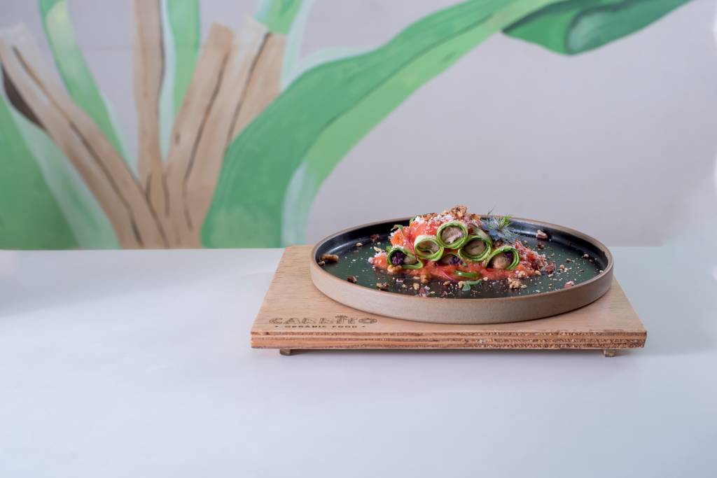 Carrito Organic prato de cerâmica sobre suplat de madeira em cima de mesa com canelones de legumes.