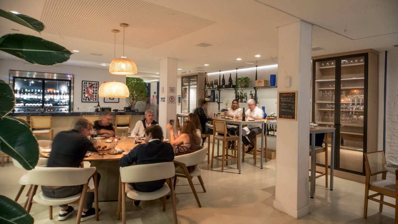 O salão do Cellar Cave, bem iluminado com paredes brancas e mesas claras ocupadas por pessoas