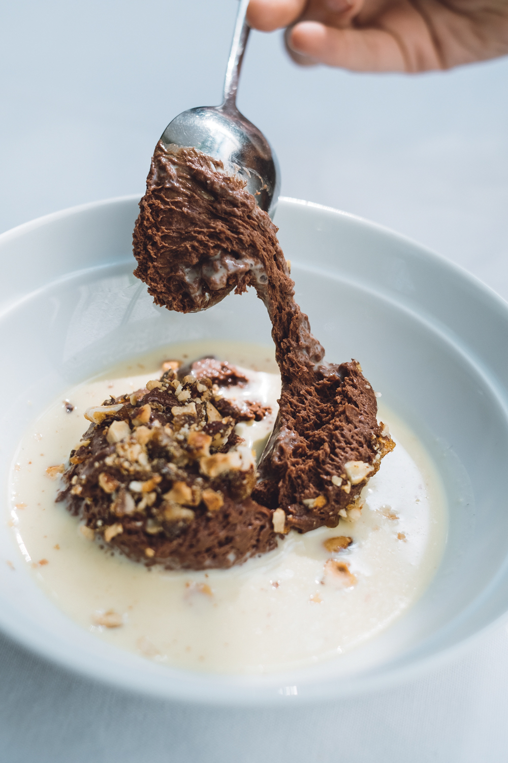 Chou Creme branco com musse de chocolate ao centro com colher pegando colherada