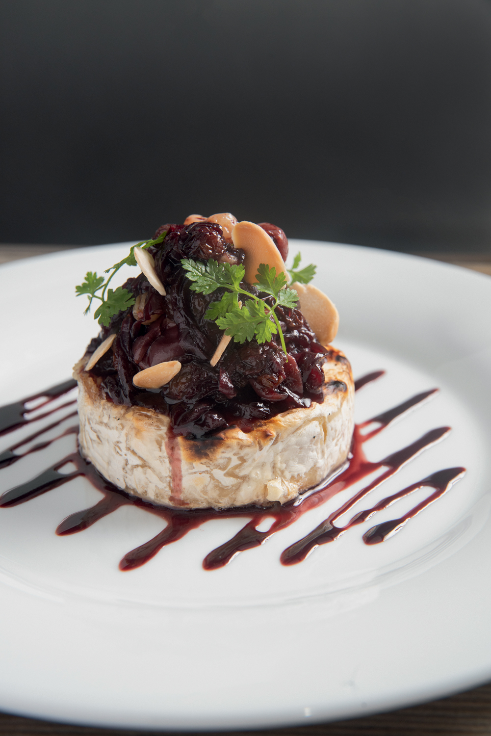 Skye – Hotel Unique Queijo brie com uvas por cima sobre prato de louça branca