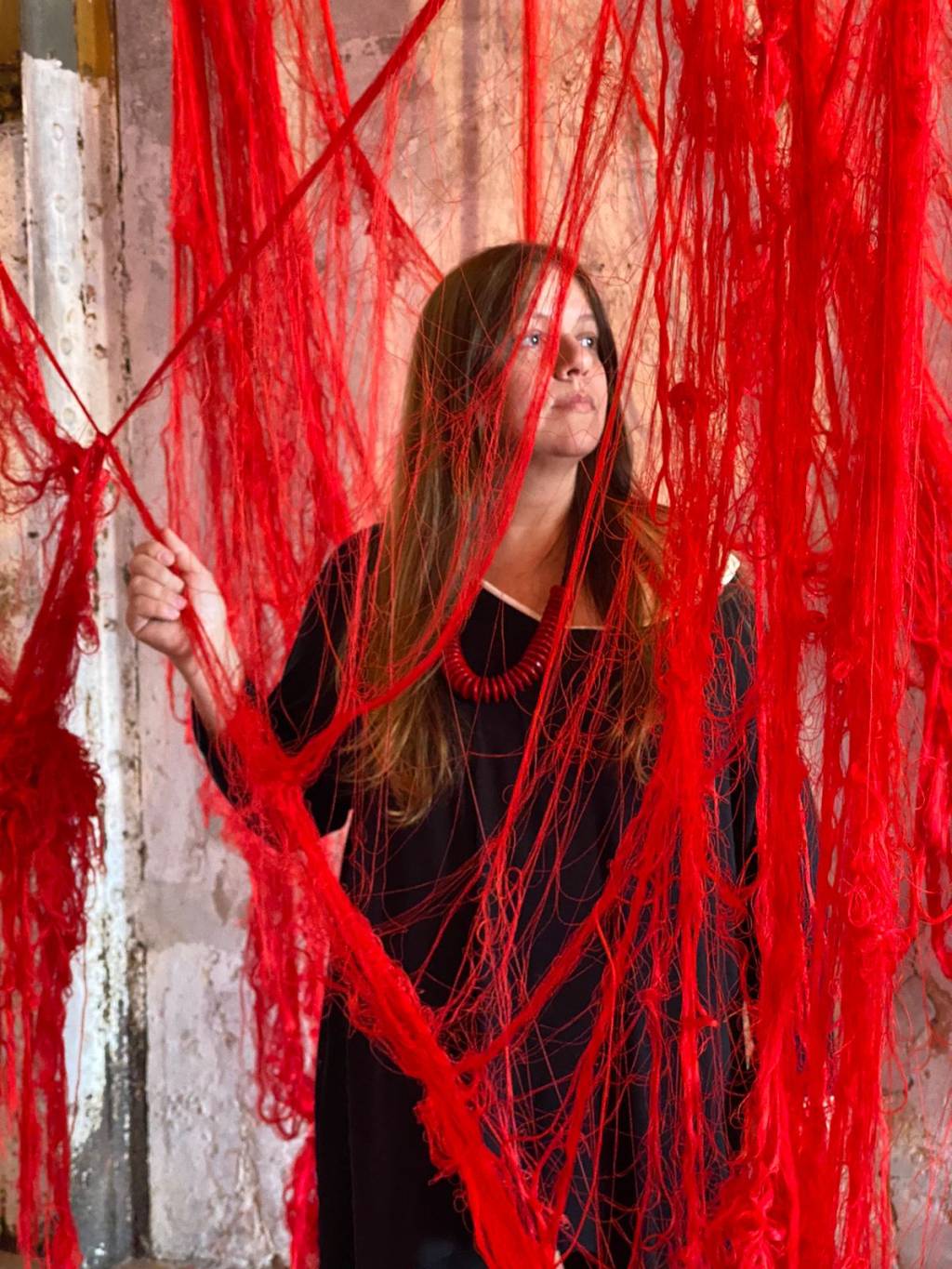 Adrianna Eu -Crédito Thiele Elissa – Acervo Pessoal (3) Mulher branca de cabelos longos posa com emaranhado de fios vermelhos na sua frente