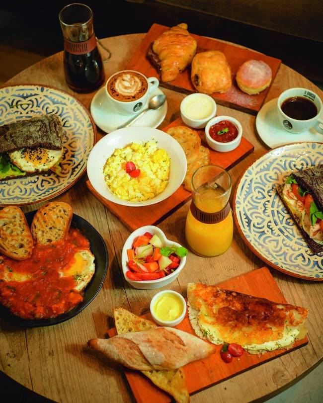 Brunch IL Barista.jpg Mesa com itens de brunch como ovos mexidos, torradas, croissant, entre outros