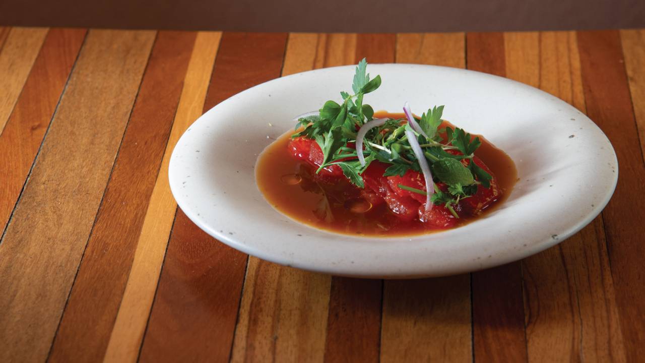 Tiradito de melancia em prato branco sobre mesa de madeira