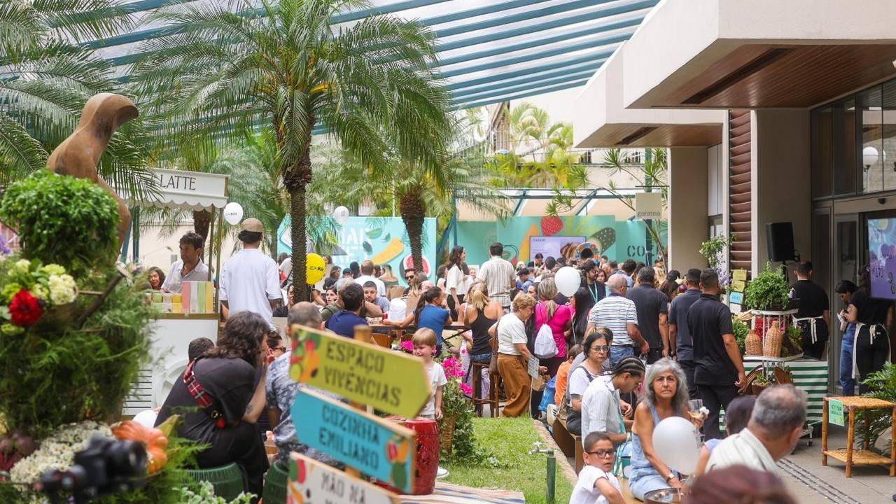 Espaço ao ar livre com visitantes caminhando por feira de gastronomia