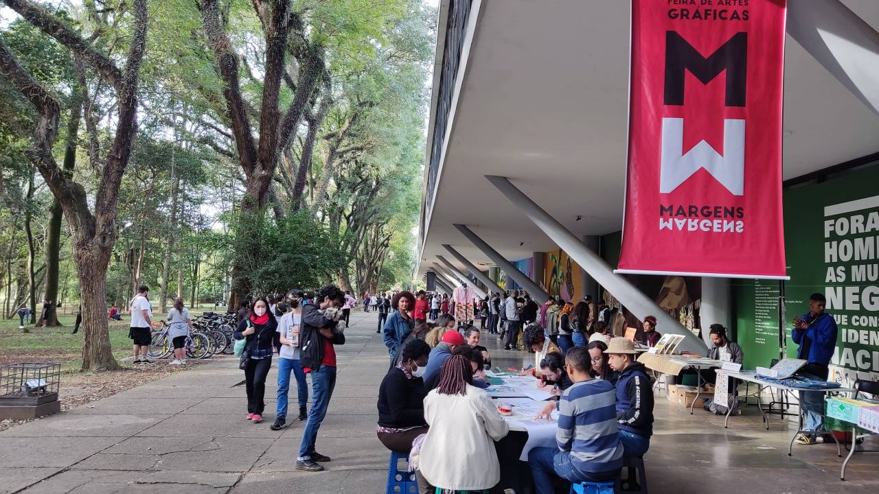 Feira com mesas e bandeira e pessoas sentadas