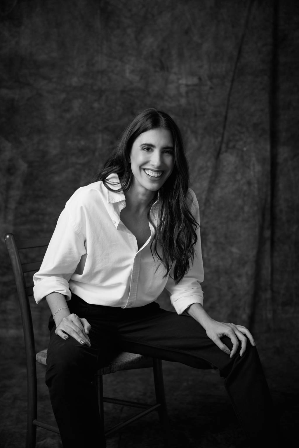 Maria Helena Crédito Manuel Nogueira-Divulgação (1) Foto em preto e branco de mulher posando em cadeira de madeira e vestindo camisa branca com calça preta