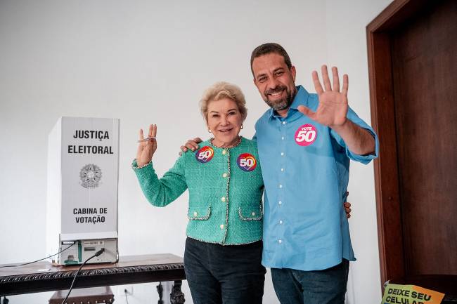 54097262743_3854f13e37_k Duas pessoas sorrindo e fazendo gesto com as mãos formando 50