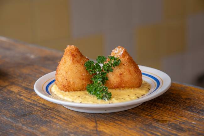 De*Primeira Prato branco com duas coxinhas.
