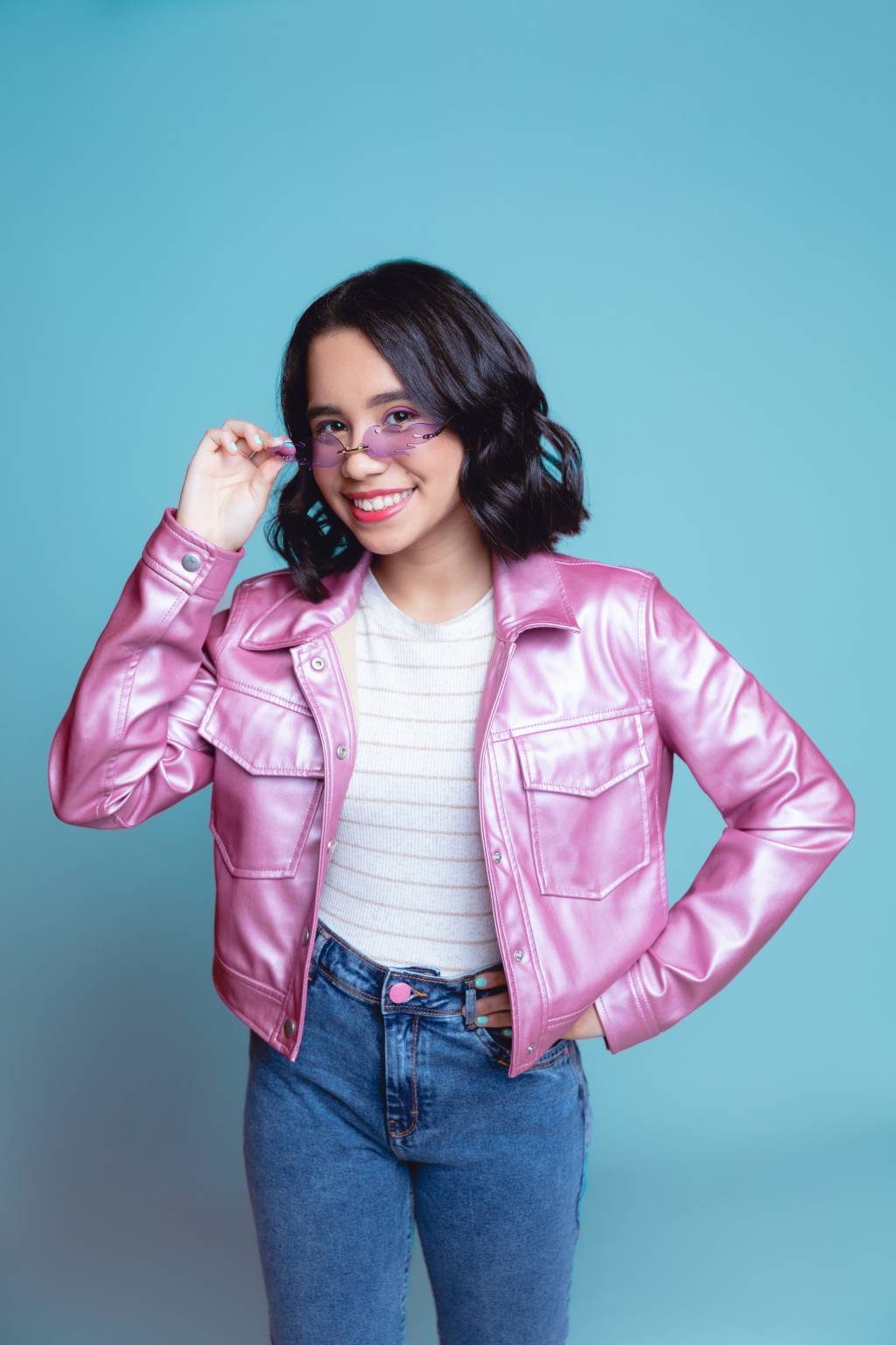 Malu Lira Crédito Alexandre Oliveires-Divulgação (5) Menina de cabelo curto posa segurando óculos rosa e vestindo jaqueta rosa com calça jeans