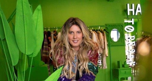Mulher loira posa em brechó com parede verde