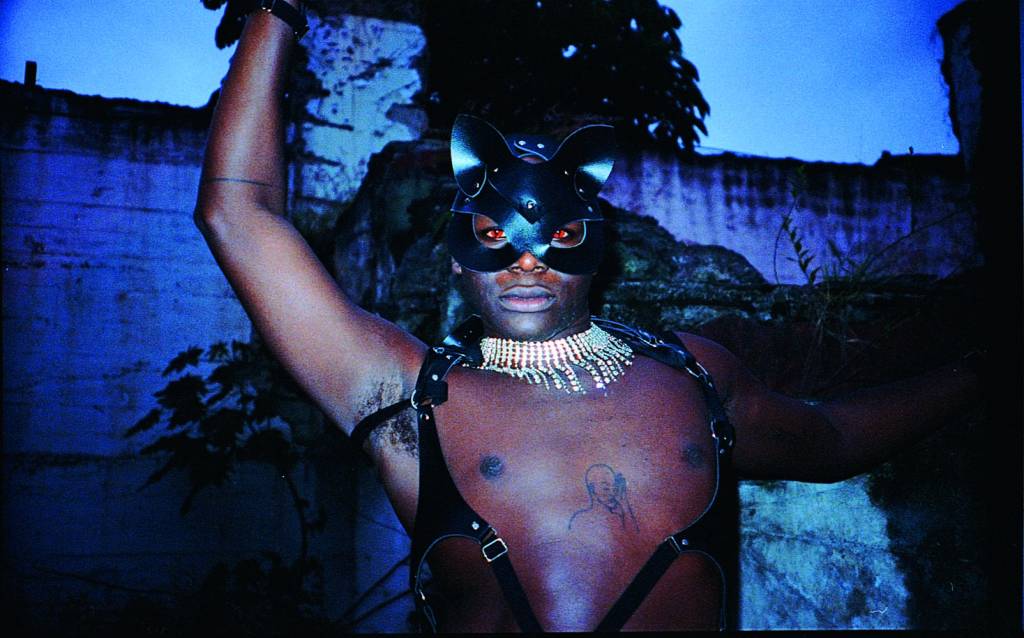 Performer Loïc Koutana no Festival Gop Tun Crédito Pedro Pinho-Reprodução Homem negro de máscara e adereços, sem camisa