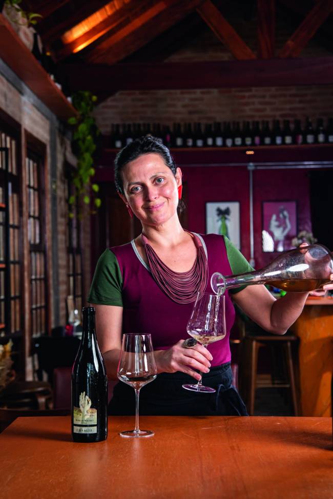 Plou Mulher segurando garrafa e servindo vinho sorrindo
