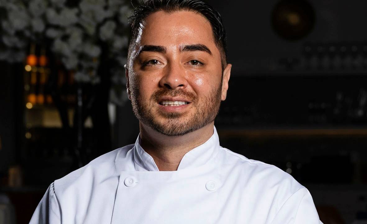 Retrato do chef Daniel Ken vestido com um jaleco branco de cozinheiro