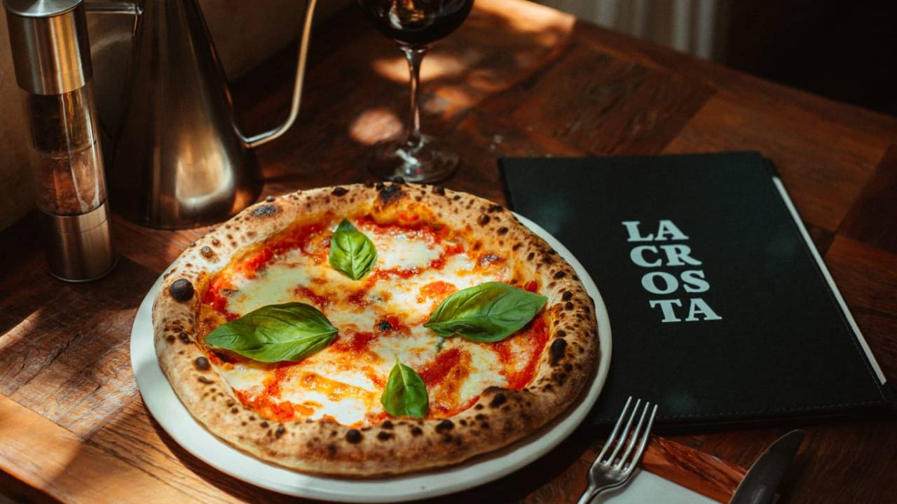 Pizza em cima do prato branco e taça de vinho