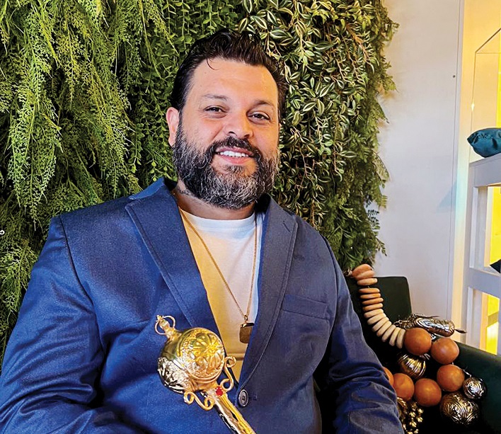 Homem de barba com paletó azul e bengala de ouro com esfera na ponta