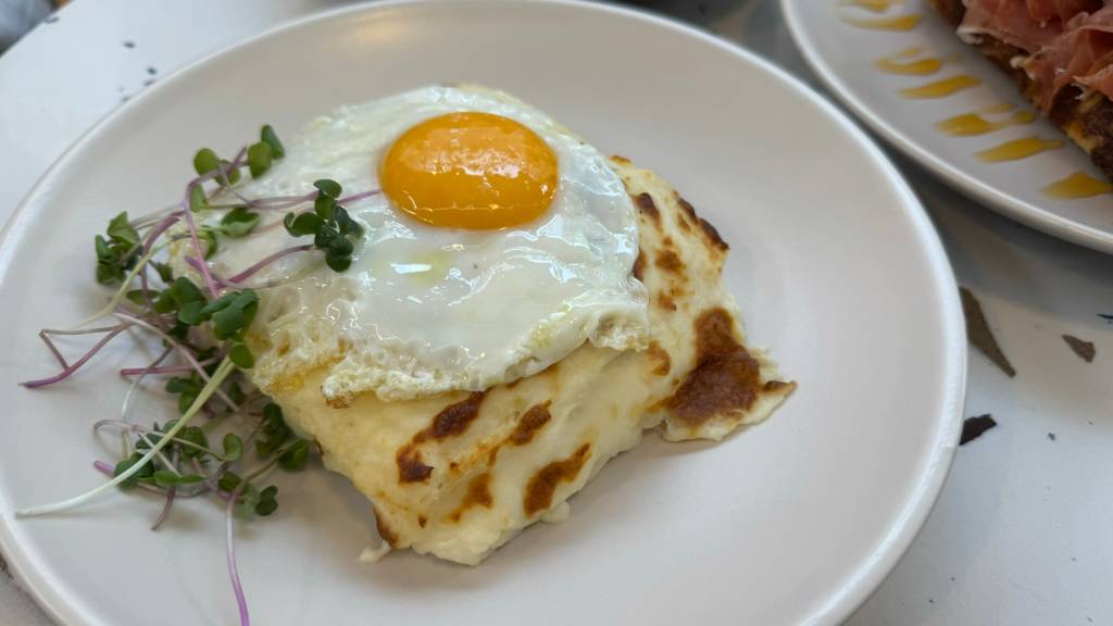 Croque madame Sanduíche de pão de miga recheado de presunto royale, queijo emmental, mostarda e molho bechamel com um ovo frito